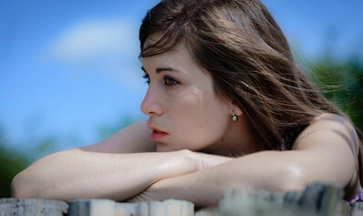 Portrait d’une femme en extérieur, regard tourné vers l’horizon, appuyée sur ses bras, lumière naturelle et ambiance douce
