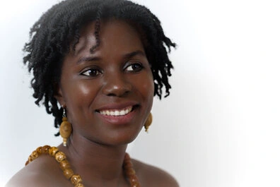 Portrait d’une femme souriante en studio sur fond clair, lumière douce et expression naturelle