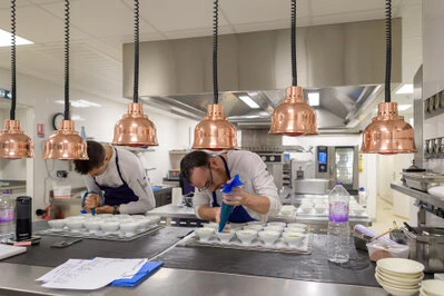 Deux cuisiniers dressant des assiettes en cuisine professionnelle avec précision et concentration