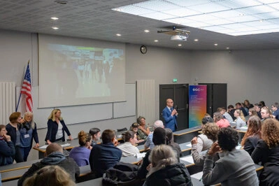 Intervenant prenant la parole devant un public dans une salle de conférence avec projection à l’écran