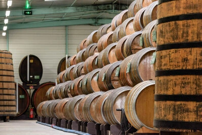 Rangées de grands fûts en bois alignés dans un espace de production ou de stockage