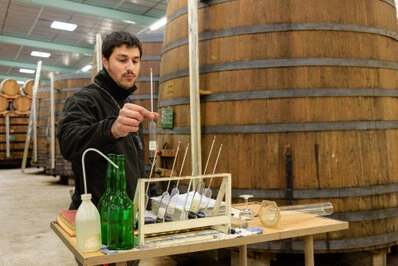 Homme réalisant une analyse avec du matériel de mesure dans un atelier avec des cuves en arrière-plan