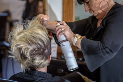 Coiffeuse appliquant un produit sur les cheveux d’une cliente dans un salon de coiffure