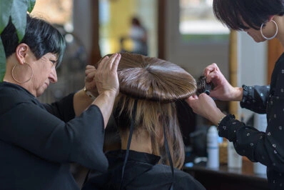 Deux coiffeuses travaillant ensemble pour réaliser une coiffure sur une cliente en salon